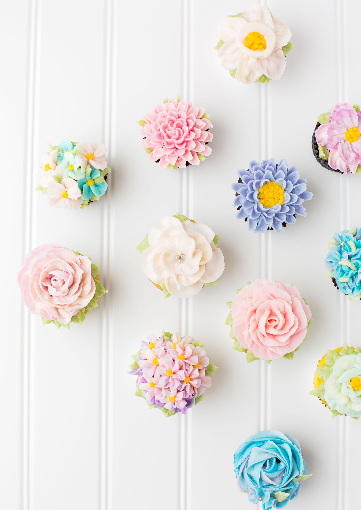 a photo of many cupcakes with icing that looks like flowers